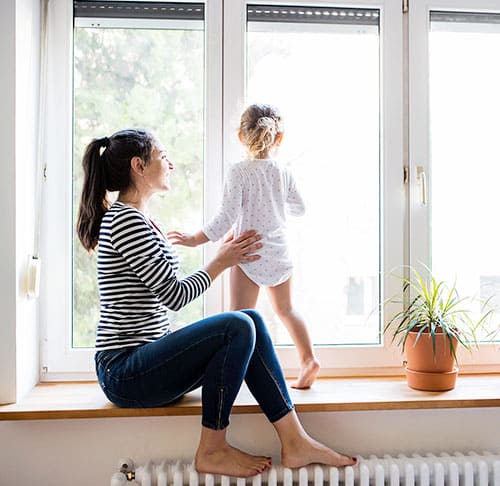 Frau mit Kind vor einem Fenster